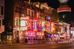 a city street at night with buildings lit up and neon signs on the side of it