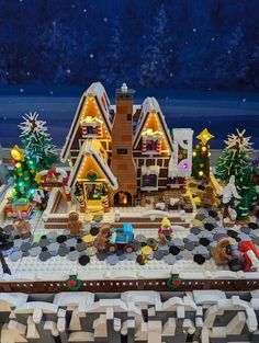 a lego christmas village is shown with lights and decorations on the roof, along with snow - covered trees