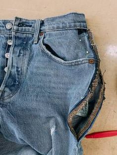 an old pair of jeans with holes in the back pocket and a red leash attached to it