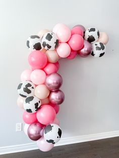 the letter c made out of balloons is decorated with black and white cow print dots