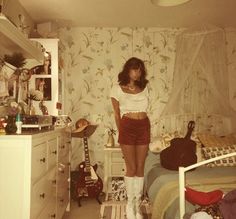 a woman in short shorts and boots standing on a bed