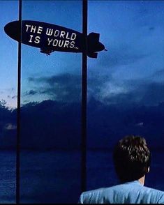 a man standing in front of a sign that says the world is yours