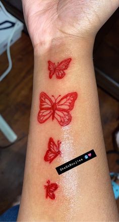 a woman's wrist with three red butterflies on the left side of her arm