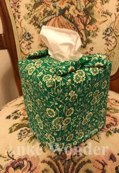 a tissue box sitting on top of a chair covered in a green and white cloth