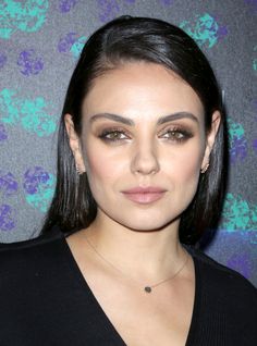 a close up of a person wearing a black shirt and necklace with flowers in the background