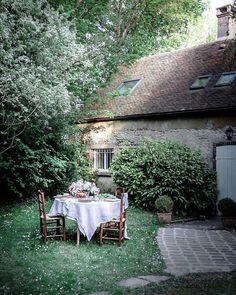 the table is set outside in the yard for two people to sit down and eat