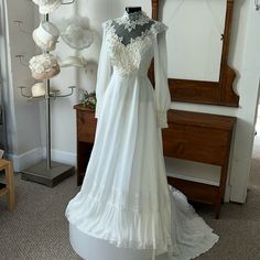 a white wedding dress is on display in front of a mirror and some other items