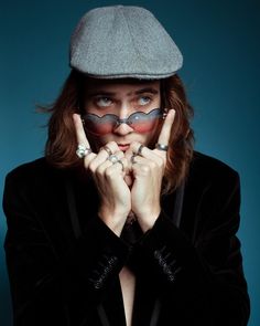 a woman with fake mustaches on her face wearing a newsboy hat and glasses