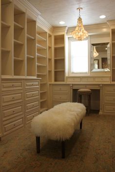 a white sheepskin bench sitting in front of a closet filled with lots of drawers