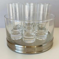 a set of six glasses sitting on top of a metal stand with silver rims