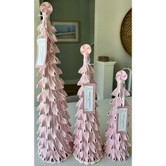 three pink christmas trees with tags on them sitting on top of a table next to a mirror