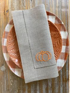 an orange and white plate with a napkin on it next to a pumpkin shaped dish towel