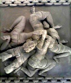 an intricately carved sculpture depicting three men wrestling in front of another man's head