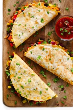 three quesadillas on a cutting board with salsa