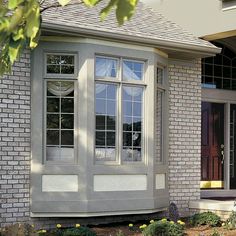 a house that has some flowers in the front yard and windows on the side of it