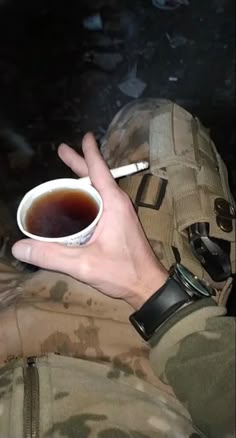 a person in camouflage holding a cup of tea