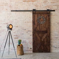 a wooden door sitting in front of a brick wall next to a tripod light