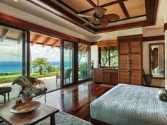 a bedroom with wood floors and large windows looking out onto the ocean from it's master suite