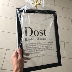 a person holding up a plastic bag with the words dost on it and a gold bow