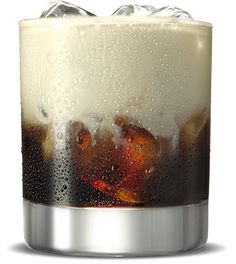 a glass filled with ice and soda on top of a table