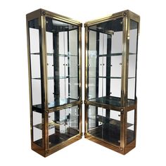 two gold and black glass display cases with shelves on each side, one is open