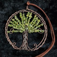 a wire tree with green beads hanging from it's center, on a black background