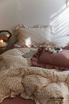 an unmade bed with pink sheets and pillows on it, in front of a window