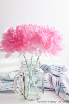 pink carnations in a mason jar with striped straws on the tablecloth