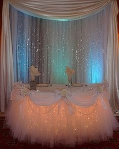 the table is set up with white linens and tulle skirted drapes