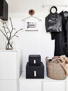 a black leather jacket hanging on a white wall next to a basket with clothes in it