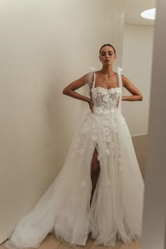 a woman in a white wedding dress standing next to a mirror