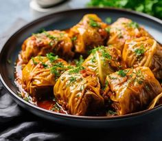 cabbage stuffed with meat and garnished with parsley in a black bowl on a table