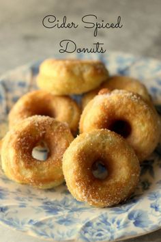 some sugared donuts on a blue and white plate with the words cider spiced donuts