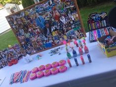 the table is set up with various items for an art show or birthday party, including cupcakes and candy