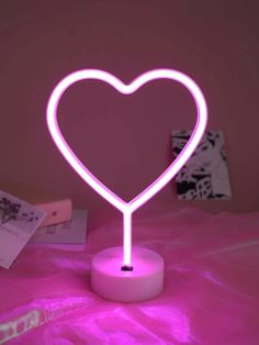 a heart shaped neon light sitting on top of a table