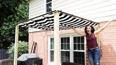 a woman is standing under an awning in front of a house with her arms outstretched