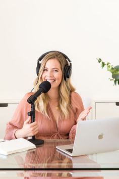 a woman wearing headphones sitting at a desk with a laptop and microphone in front of her