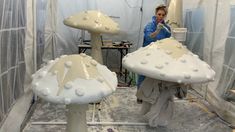 a woman standing in front of two mushroom shaped structures with white frosting on them