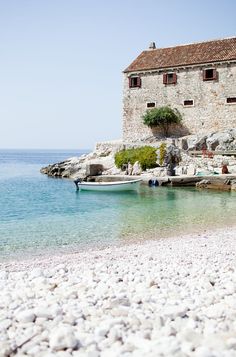 there is a small boat on the water near an old stone building that has been built into it