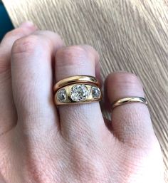 a woman's hand with two gold rings on top of her finger and the other one has a diamond in it