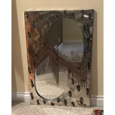 a mirror that is sitting on the floor in front of a wall with holes and nails