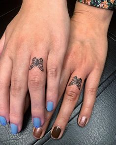 two people with matching tattoos on their fingers, one has a bow and the other has a heart