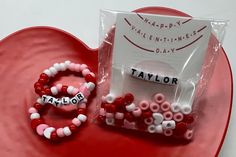 valentine's day bracelets and beads on a heart shaped plate with a happy valentine's day card