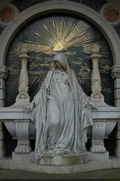 black and white photograph of the statue of mary in front of an ornate arch with sunburst above it