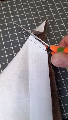 someone is cutting fabric with scissors on top of the piece of cloth that they are holding