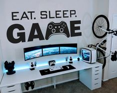 a computer desk with two monitors and a bike on top of it in front of a wall that says eat sleep gage