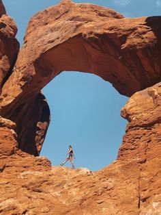 a person is running through the rocks in front of an arch