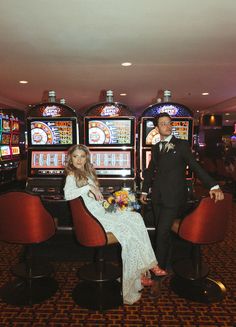 a bride and groom sitting on chairs in front of slot machines at a hotel or casino