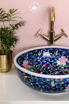 a blue flowered bowl sink sitting on top of a counter next to a potted plant