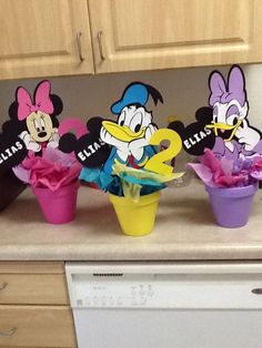 mickey mouse and friends cupcake toppers on a kitchen counter with flowers in them